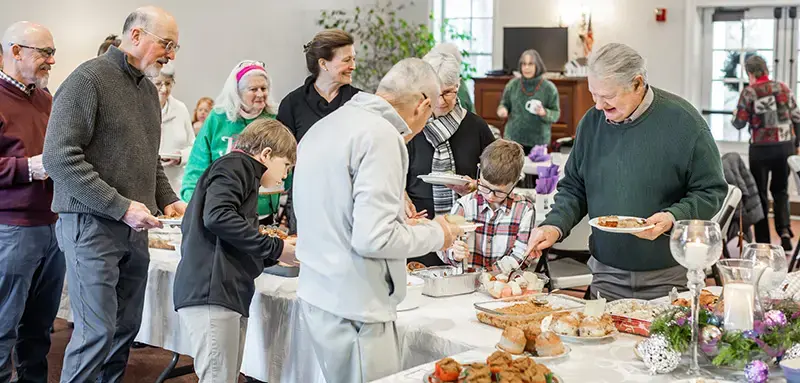 Parishioners of all ages gather around a buffet table at an Advent lunch in the parish hall