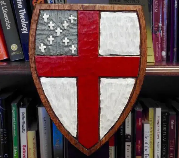 A handcrafted wooden Episcopal Church shield displayed in front of theology books