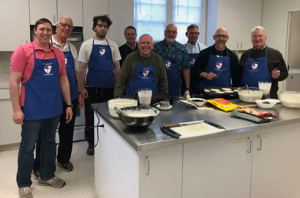 Men's group members wearing Grace Church aprons gather in the kitchen to prepare a pancake breakfast